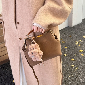 Sac rétro en daim marron avec cadre en métal doré et breloque peluche sur manteau d'hiver