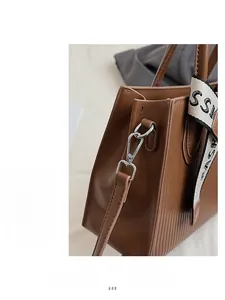 Detail view of brown leather bag with metallic clasp and decorative fashion scarf