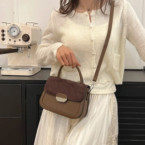 Brown patchwork saddle handbag with metal buckle shown in a stylish lifestyle setting