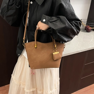 Brown matte leather tote bag with gold hardware and a small coin purse pendant
