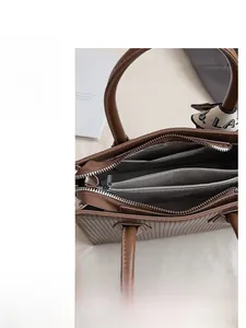 Detail view of brown tote bag interior with multiple compartments and silk scarf handle