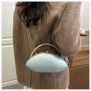 Light blue oval acrylic evening bag with gold ring handle worn over a brown blazer