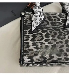 Close-up of leopard print handbag with heart silk scarf and branded pattern wide strap