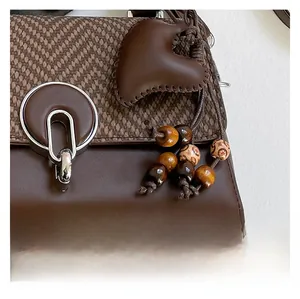 Detalle del bolso bandolera marrón con colgante de corazón y borlas de cuentas étnicas