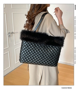 Detail of black quilted tote bag featuring plush faux fur trim and leather straps on model