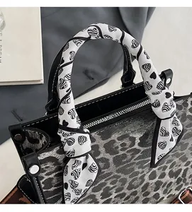 Detail of leopard print handbag with heart pattern silk scarf wrapped handle and silver hardware