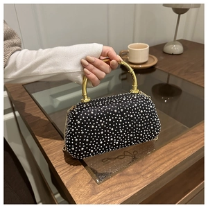 Close-up of black evening bag with white rhinestones and a gold bamboo-style handle