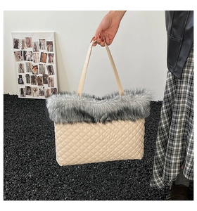 Detail of beige quilted tote bag featuring grey faux fur trim and textured stitching