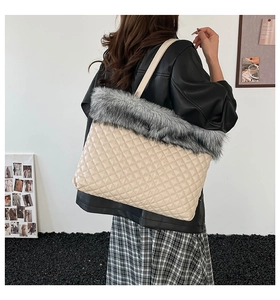 Macro detail of beige quilted leather texture and thick grey faux fur trim on the tote bag