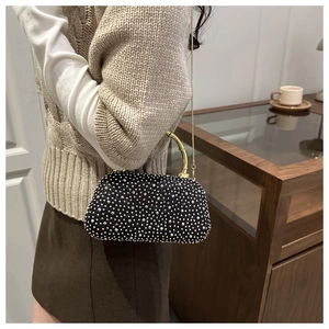 Detail of black evening clutch bag with sparkling rhinestones and golden handle