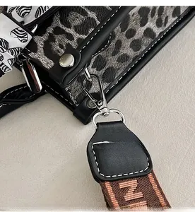 Close-up of leopard print fabric with silver metal hooks and black leather trim