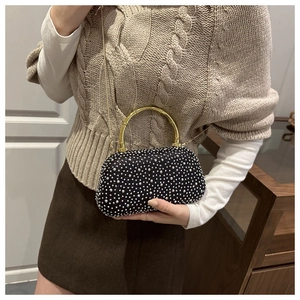 Close-up of black evening bag with sparkling rhinestones and golden circular handle