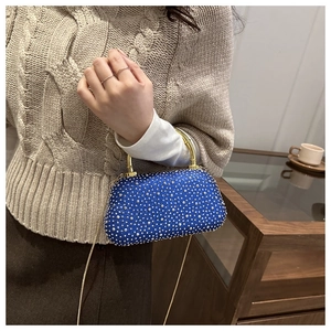 Detail of blue rhinestone evening bag with gold metal handle and chain strap on a model