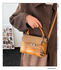 Detail of caramel leather handbag with herringbone weave flap and heart charm