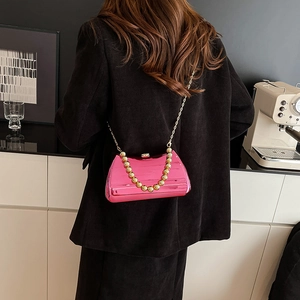 Hot pink metallic box clutch with gold bead handle and acrylic chain shown on model