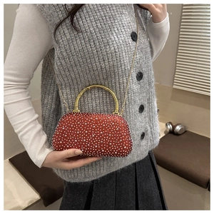 Detail of red rhinestone evening bag with gold bamboo handle and chain strap on model
