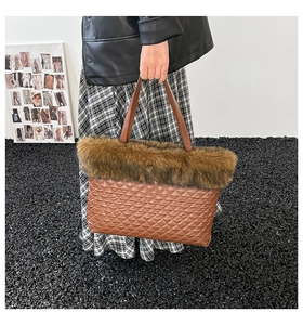 Detail of a brown quilted tote bag with faux fur trim held by a model in a leather jacket