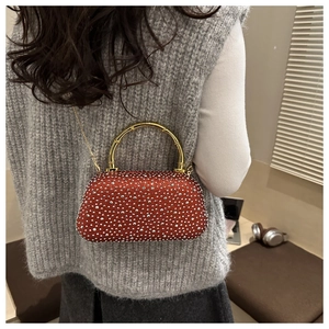 Macro detail of red-brown evening bag with rhinestones and golden bamboo handle