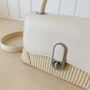 Detail of premium crossbody bag showing textured woven straw and smooth leather stitching