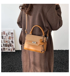Detail of checkered woven flap and leather finish on brown top handle crossbody bag