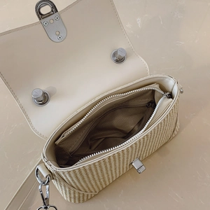 Detail view of woven straw bag interior with synthetic leather trim and metal twist lock