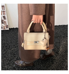 Detail of beige color-block handbag featuring woven texture and silver twist lock