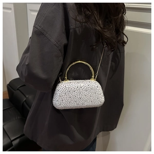 Close-up of white evening bag with rhinestones, gold bamboo handle and chain strap