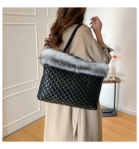 Detail of a black quilted tote bag with soft faux fur trim and leather shoulder strap