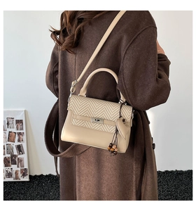 Detail of a chic cream leather and herringbone woven handbag with silver metal turn-lock