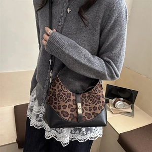 Leopard and rose print crossbody bag with gold buckle in a modern cafe setting