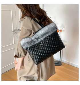 Detail view of quilted black leather tote bag with stylish grey faux fur trim and long strap