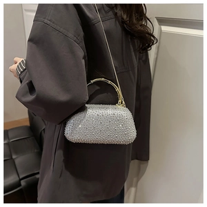 Detail of silver rhinestone evening bag with gold handle held by model in brown coat