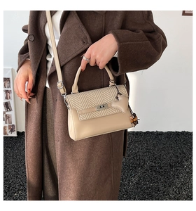 Detail of beige plaid crossbody bag with weave texture and heart-shaped pendant detail