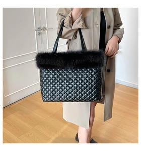 Detailed close-up of quilted black tote bag with plush faux fur trim and thin shoulder straps