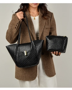 Dettaglio della borsa tote nera intrecciata con chiusura dorata su un elegante blazer marrone