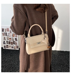 Detail of elegant apricot crossbody bag with heart pendant on wool coat backdrop