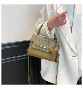 Detail of checkered woven texture and green leather shoulder bag with heart charm