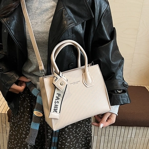 Chic beige textured square handbag with top handles and fashion ribbon detail