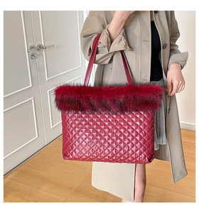 Detail of burgundy quilted tote bag with faux fur trim shown in a cozy home interior setting