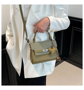 Close-up of olive green houndstooth handbag with silver twist lock and heart charm