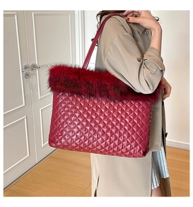 Detail of red quilted tote bag featuring plush faux fur trim and diamond stitch pattern