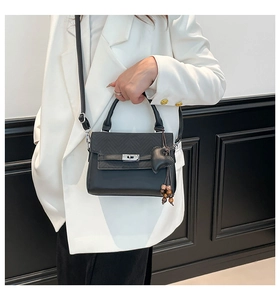 Detail of black V-quilted handbag with silver twist lock and heart charm accessory