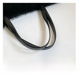 Close-up of the black plush tote bag showing a leather strap and soft fluffy texture
