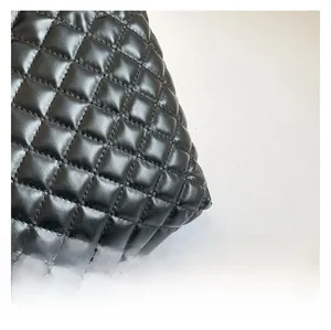 Macro view of quilted leather texture and high-gloss stitching on black tote bag