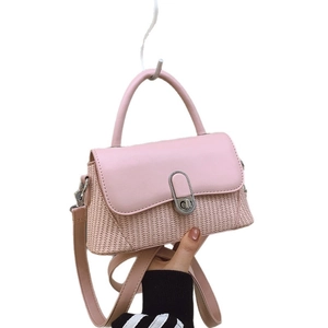 Pink patchwork handbag with top handle and woven panel shown in a front view