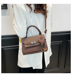 Brown plaid crossbody bag shown on shoulder with heart charm and beaded detail