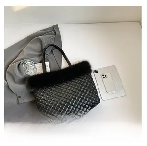 Detailed top view of black quilted tote bag with faux fur trim next to an iPad