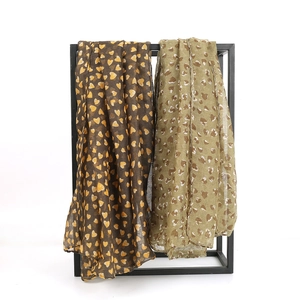 Lightweight heart print voile scarf in dark brown and olive green on a display rack