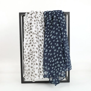 Detail of heart print scarves hanging on a metal rack showing fabric drape and texture