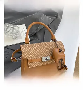 Detail of vintage crossbody bag with brown leather V-pattern weaving and heart pendant